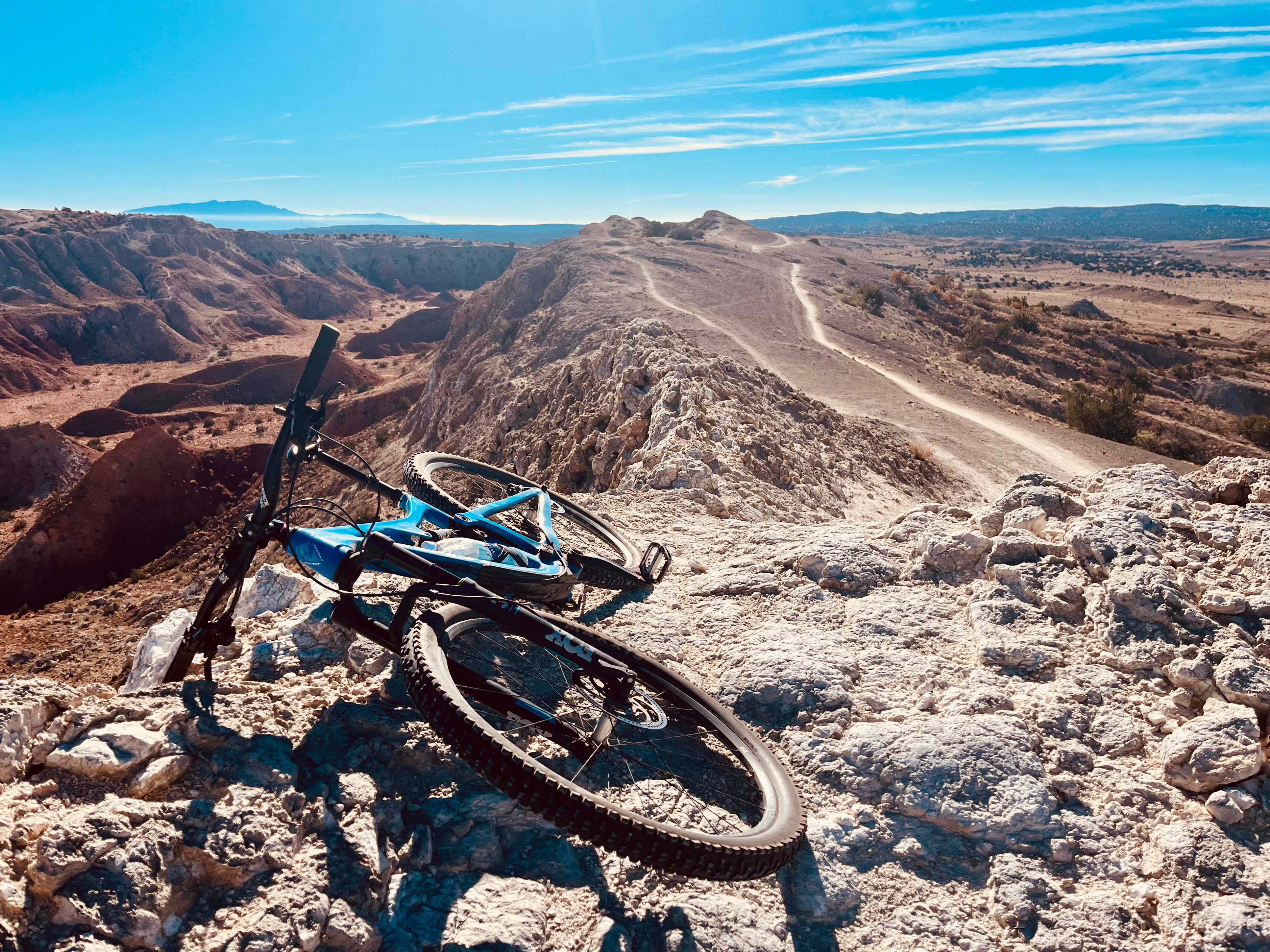 Blue mountain bike resting on rocks with a trail in the background